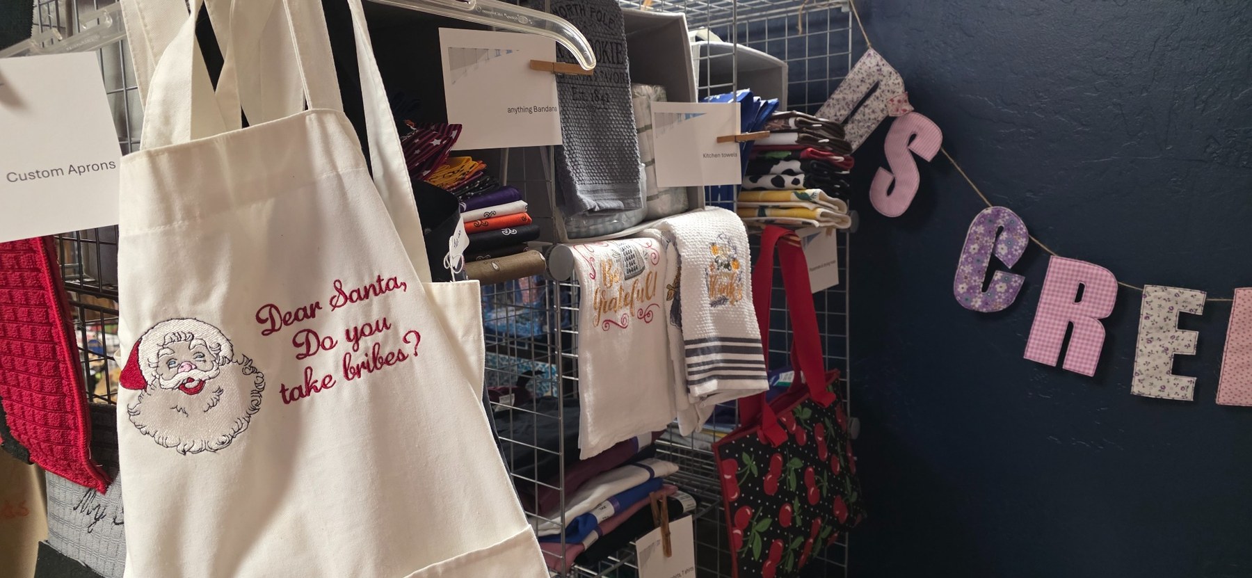 An embroidered Santa apron and decorative kitchen towels in Debbie Martin's display